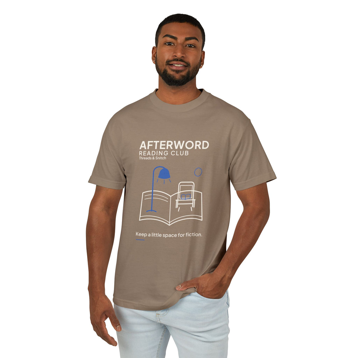 Model mockup of Afterword Reading Room Tee in Faded Brown, front view showing open book forming a room with an armchair and blue lamp.