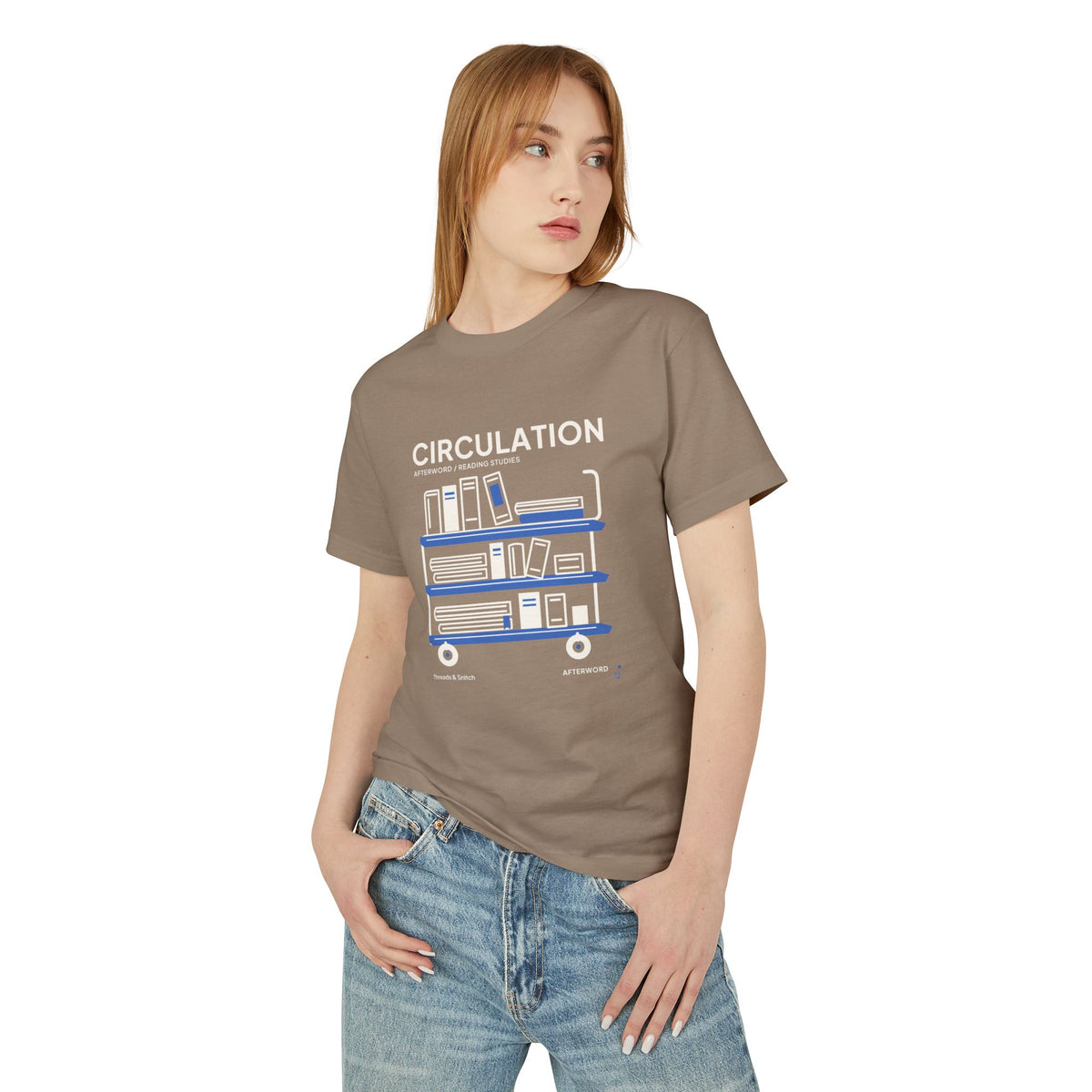 Model mockup of Circulation Library Cart Tee in Faded Brown, front view showing three-tier library cart filled with books and blue shelves.
