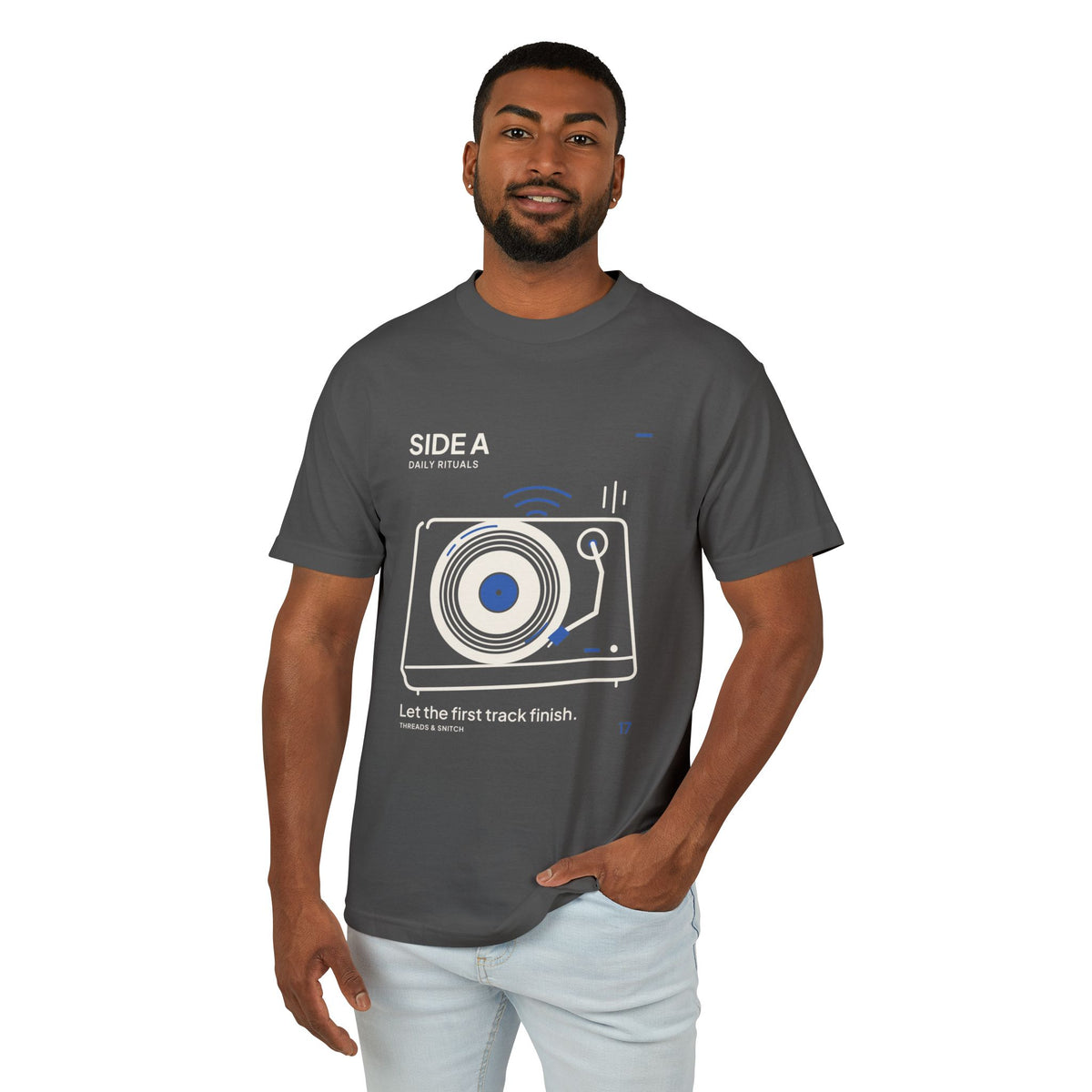 Model mockup of Side A Record Player Tee in Faded Black, front view showing record player with open circular grooves, tonearm and blue sound marks.