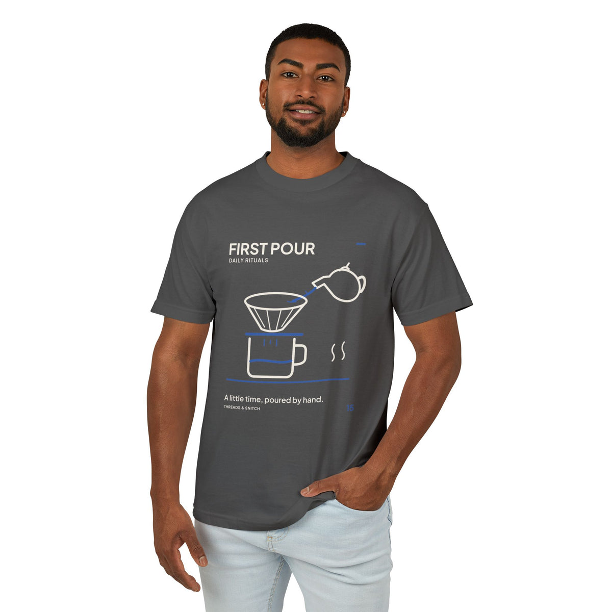 Model mockup of First Pour Coffee Graphic Tee in Faded Black, front view showing kettle pouring blue water into a coffee filter above a brew pot.