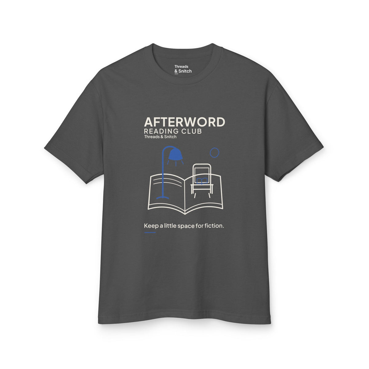 Mockup of Afterword Reading Room Tee in Faded Black, front view showing open book forming a room with an armchair and blue lamp.