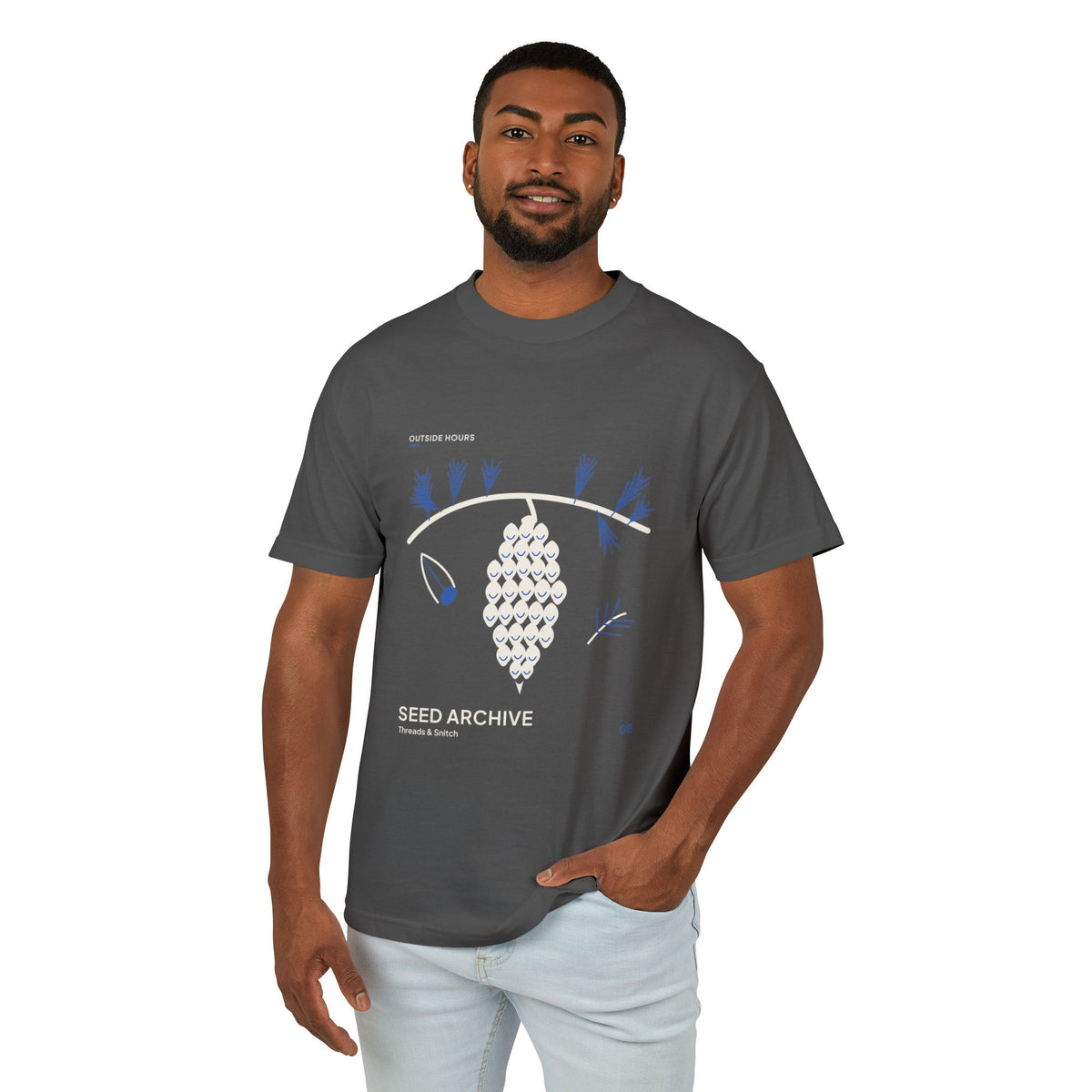 Model mockup of Seed Archive Pinecone Tee in Faded Black, front view showing pinecone beneath needle sprays with a separate winged seed.