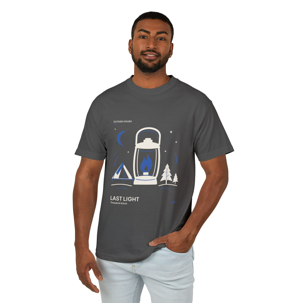 Model mockup of Last Light Lantern Graphic Tee in Faded Black, front view showing lantern, tent, trees and blue crescent moon.