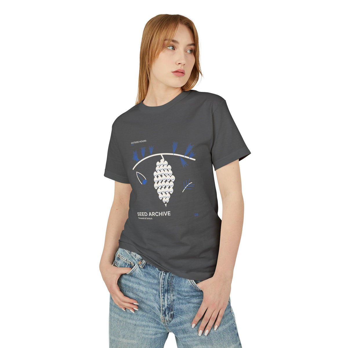 Model mockup of Seed Archive Pinecone Tee in Faded Black, front view showing pinecone beneath needle sprays with a separate winged seed.