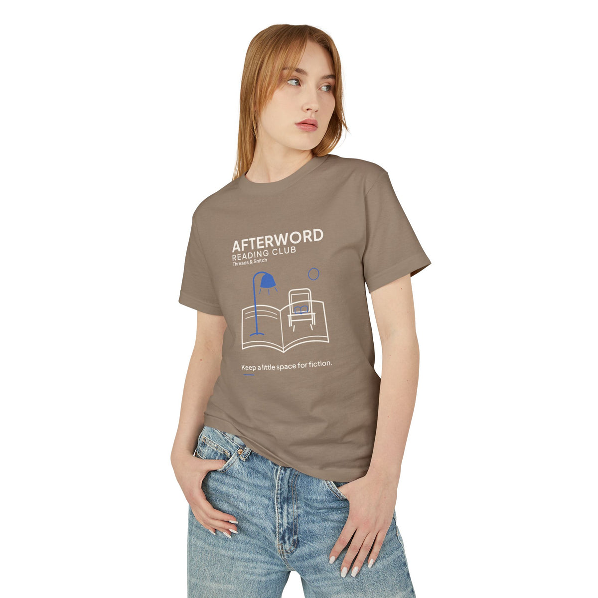 Model mockup of Afterword Reading Room Tee in Faded Brown, front view showing open book forming a room with an armchair and blue lamp.