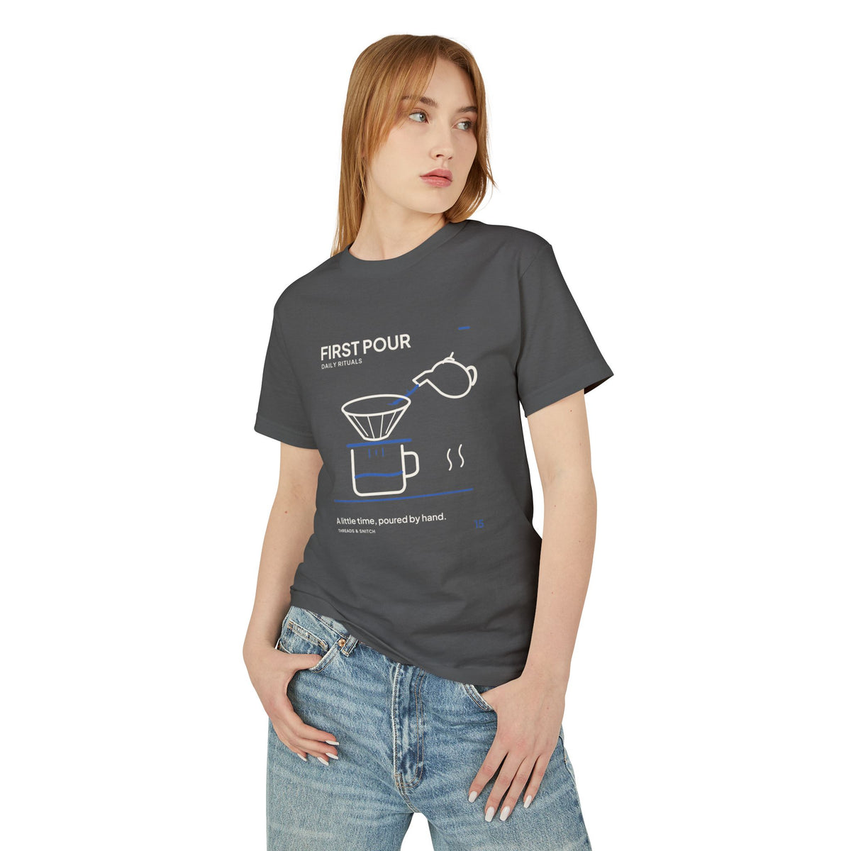 Model mockup of First Pour Coffee Graphic Tee in Faded Black, front view showing kettle pouring blue water into a coffee filter above a brew pot.