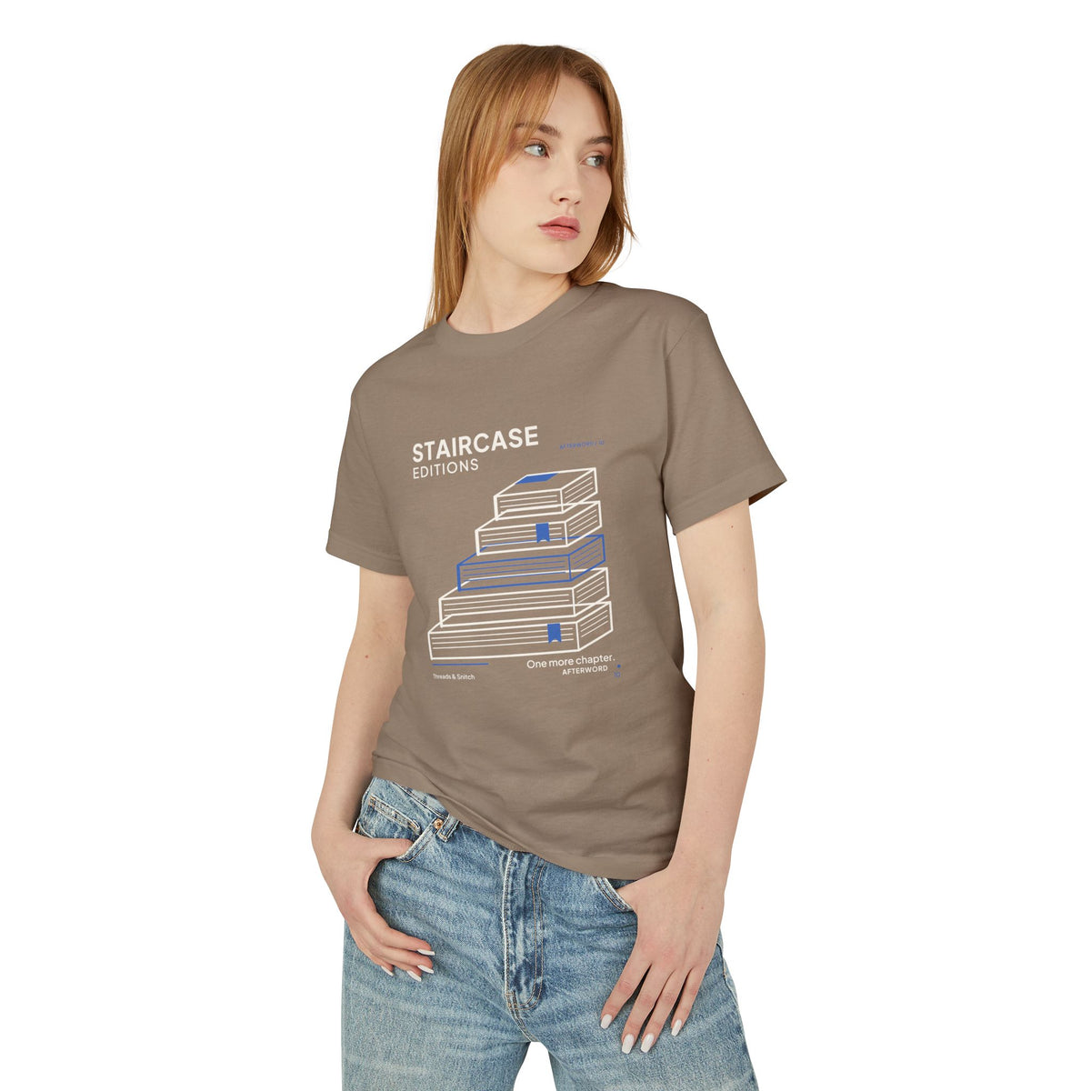 Model mockup of Staircase Editions Book Stack Tee in Faded Brown, front view showing five staggered books forming stairs with blue bookmarks.