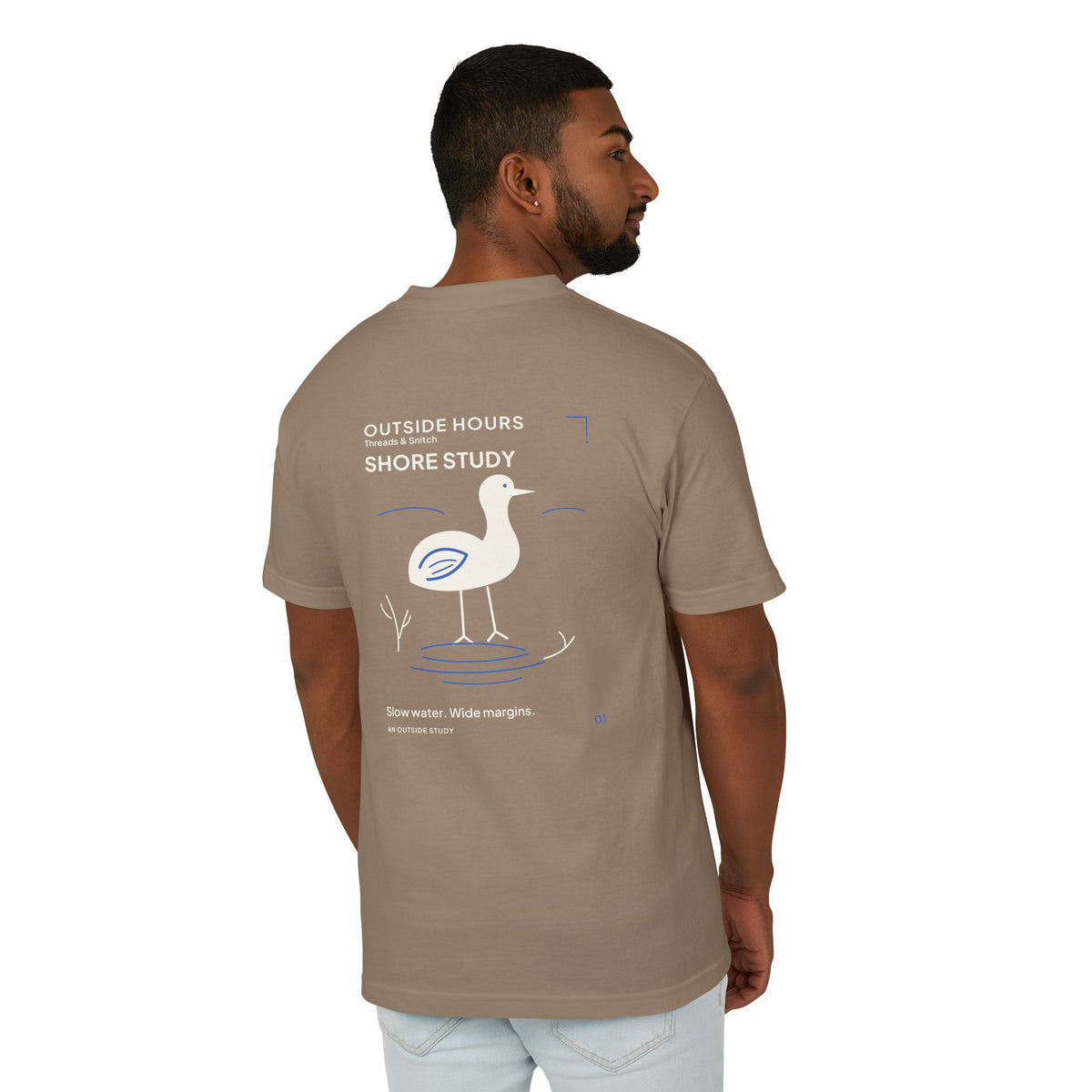 Back-view model mockup of Shore Study Bird Graphic Tee in Faded Brown, showing the wading bird and shoreline illustration.