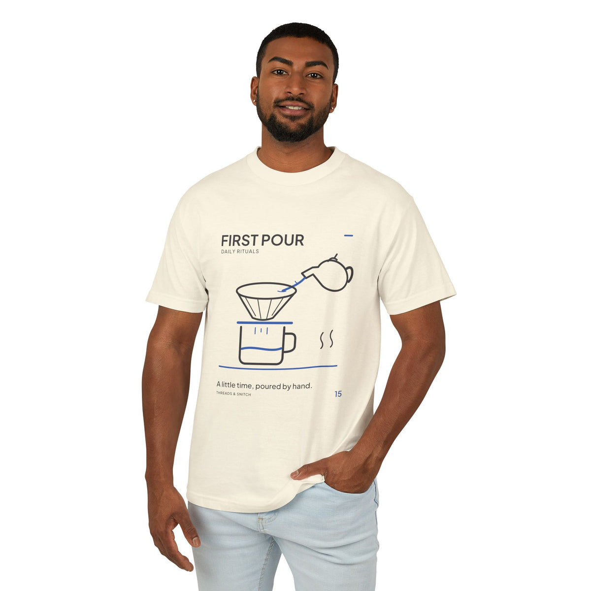 Model mockup of First Pour Coffee Graphic Tee in Faded Cream, front view showing kettle pouring blue water into a coffee filter above a brew pot.