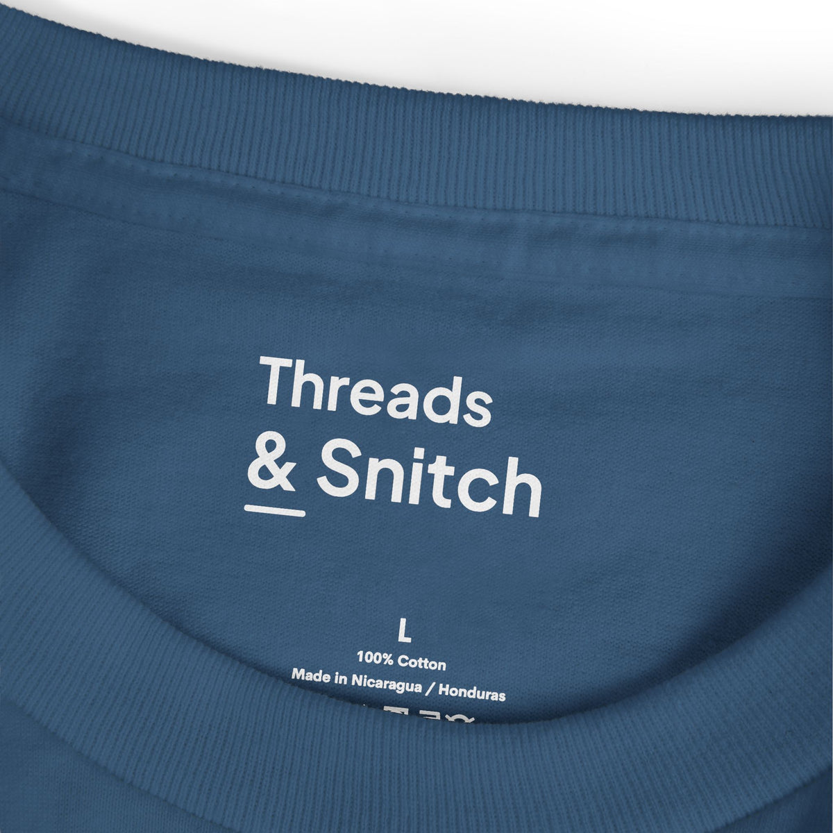 Mockup detail of the printed Threads & Snitch inner-neck label on Field of View Binoculars Tee in Faded Navy.