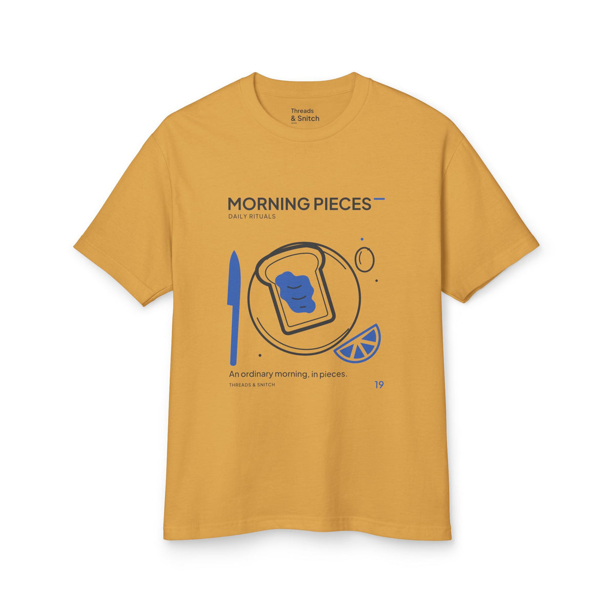 Mockup of Morning Pieces Breakfast Tee in Faded Mustard, front view showing toast on a plate beside a citrus slice and blue knife.