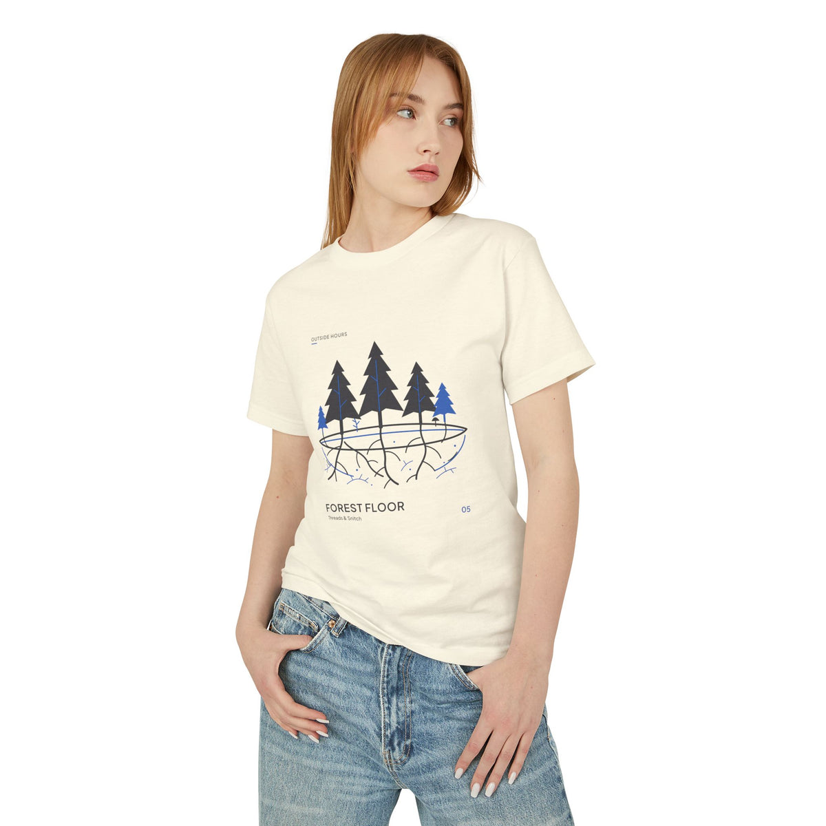 Model mockup of Forest Floor Botanical Tee in Faded Cream, front view showing five trees above exposed roots and a blue underground network.