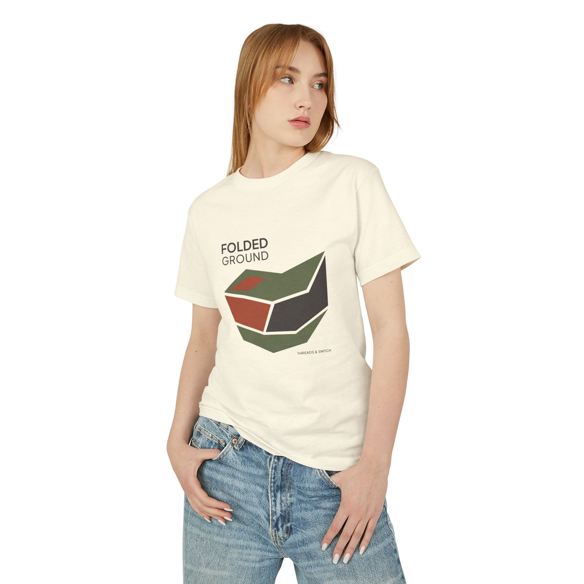 Model mockup of Folded Ground Geometric Graphic Tee in Faded Cream, front view showing angular folded planes with open channels and Folded Ground lettering.