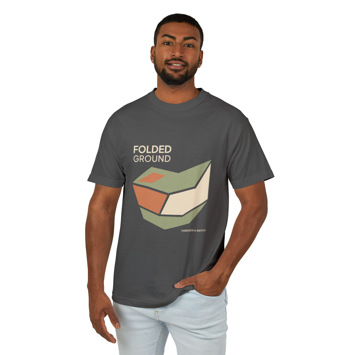 Model mockup of Folded Ground Geometric Graphic Tee in Faded Black, front view showing angular folded planes with open channels and Folded Ground lettering.