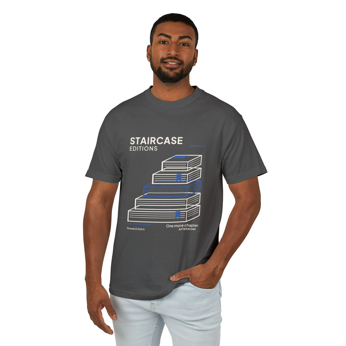 Model mockup of Staircase Editions Book Stack Tee in Faded Black, front view showing five staggered books forming stairs with blue bookmarks.