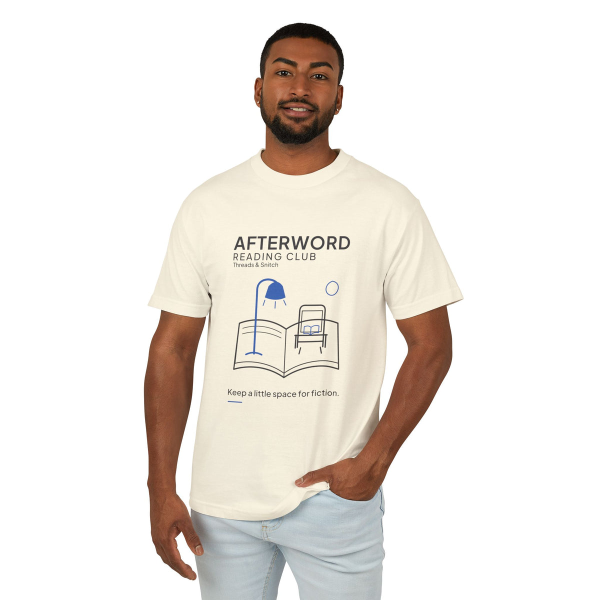 Model mockup of Afterword Reading Room Tee in Faded Cream, front view showing open book forming a room with an armchair and blue lamp.
