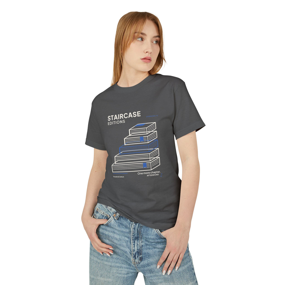 Model mockup of Staircase Editions Book Stack Tee in Faded Black, front view showing five staggered books forming stairs with blue bookmarks.