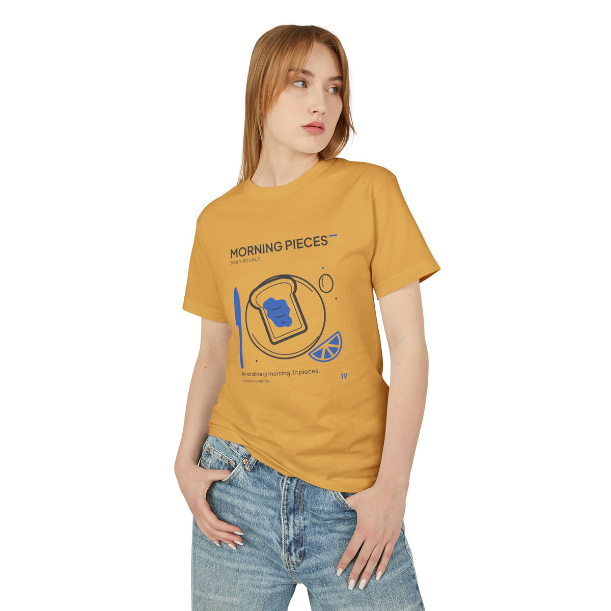 Model mockup of Morning Pieces Breakfast Tee in Faded Mustard, front view showing toast on a plate beside a citrus slice and blue knife.