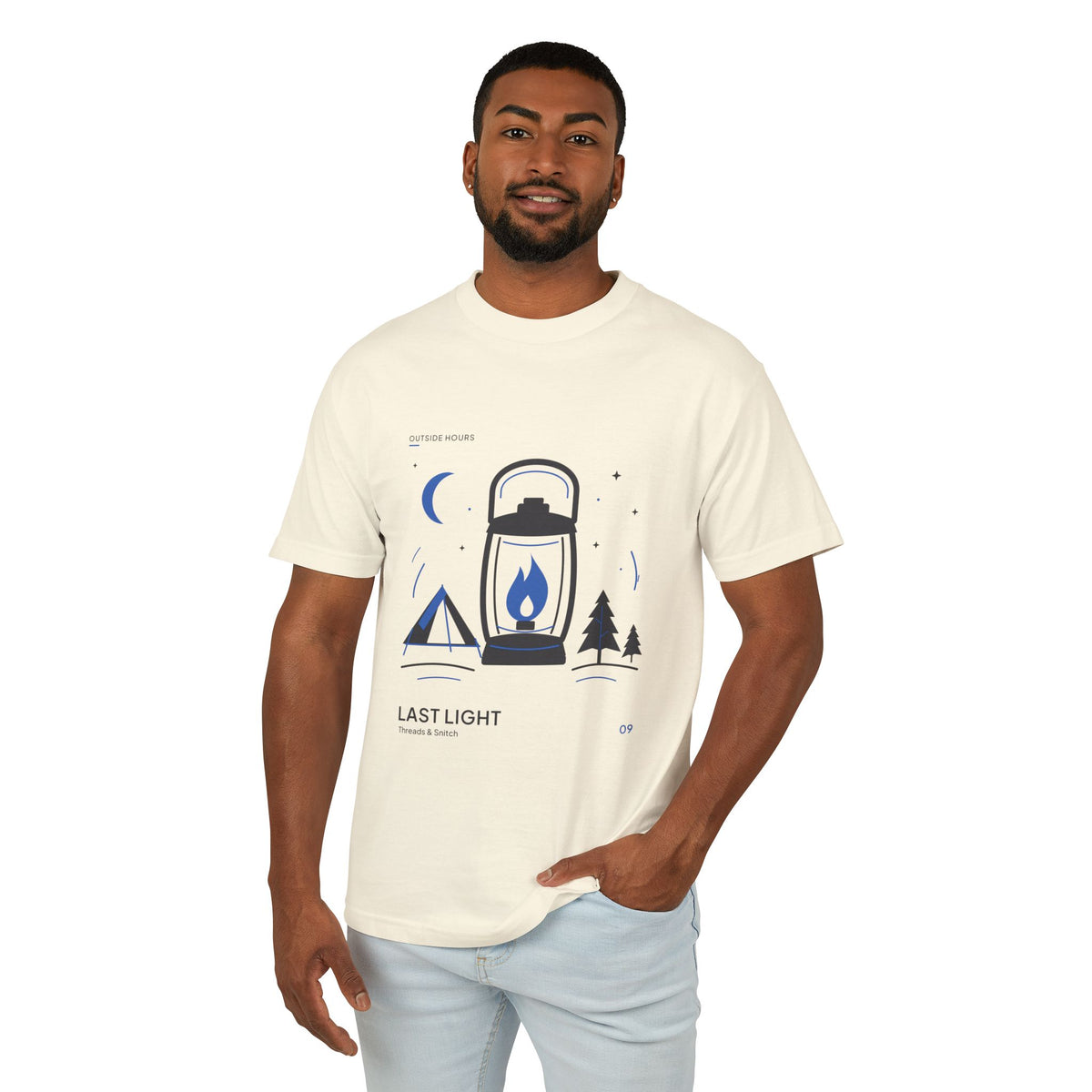Model mockup of Last Light Lantern Graphic Tee in Faded Cream, front view showing lantern, tent, trees and blue crescent moon.