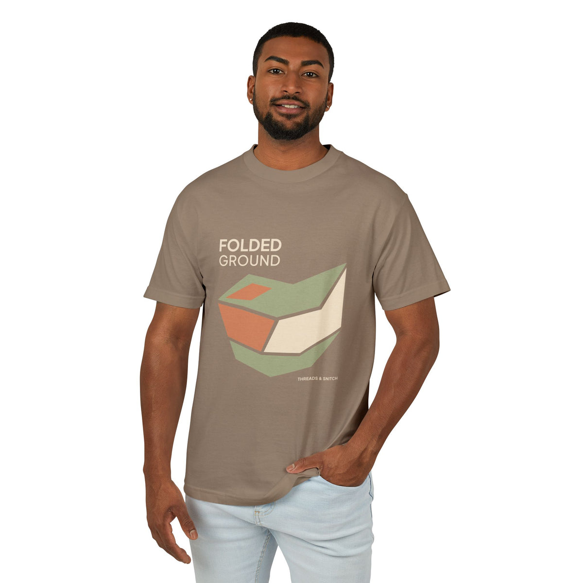 Model mockup of Folded Ground Geometric Graphic Tee in Faded Brown, front view showing angular folded planes with open channels and Folded Ground lettering.