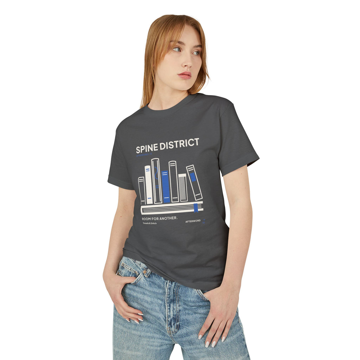 Model mockup of Spine District Book Spine Tee in Faded Black, front view showing varied book spines arranged as a skyline above a horizontal book.