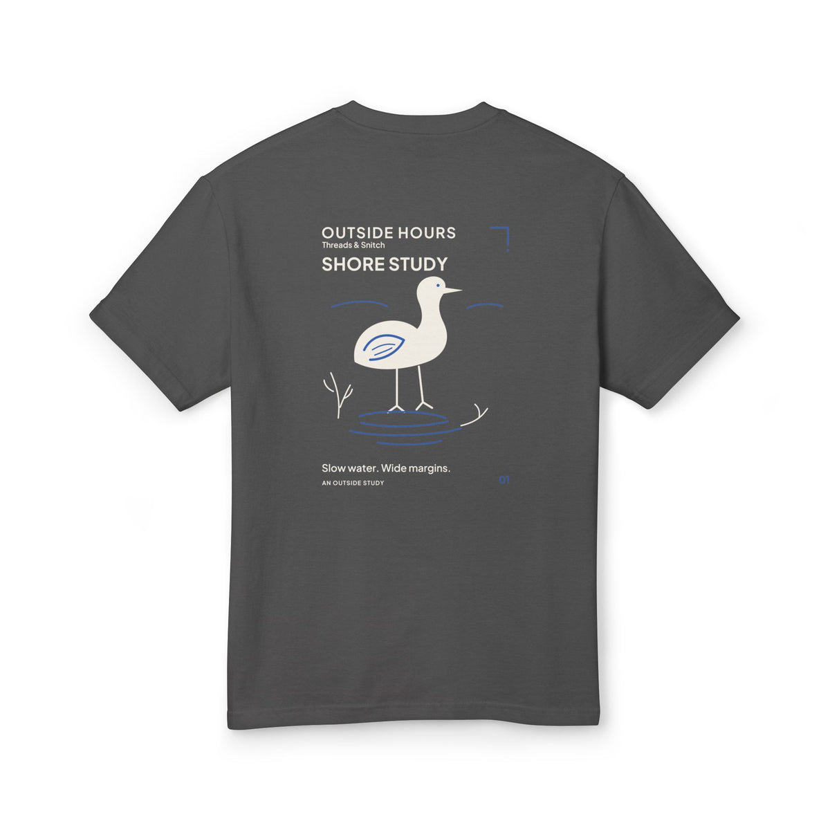 Mockup of Shore Study Bird Graphic Tee in Faded Black, back view showing wading bird, reeds and blue water ripples.