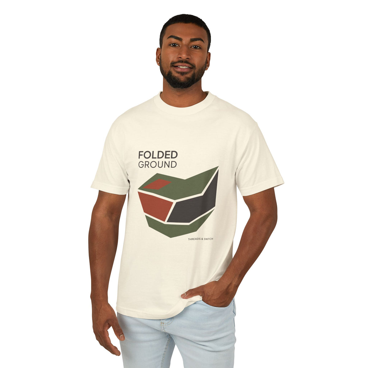 Model mockup of Folded Ground Geometric Graphic Tee in Faded Cream, front view showing angular folded planes with open channels and Folded Ground lettering.