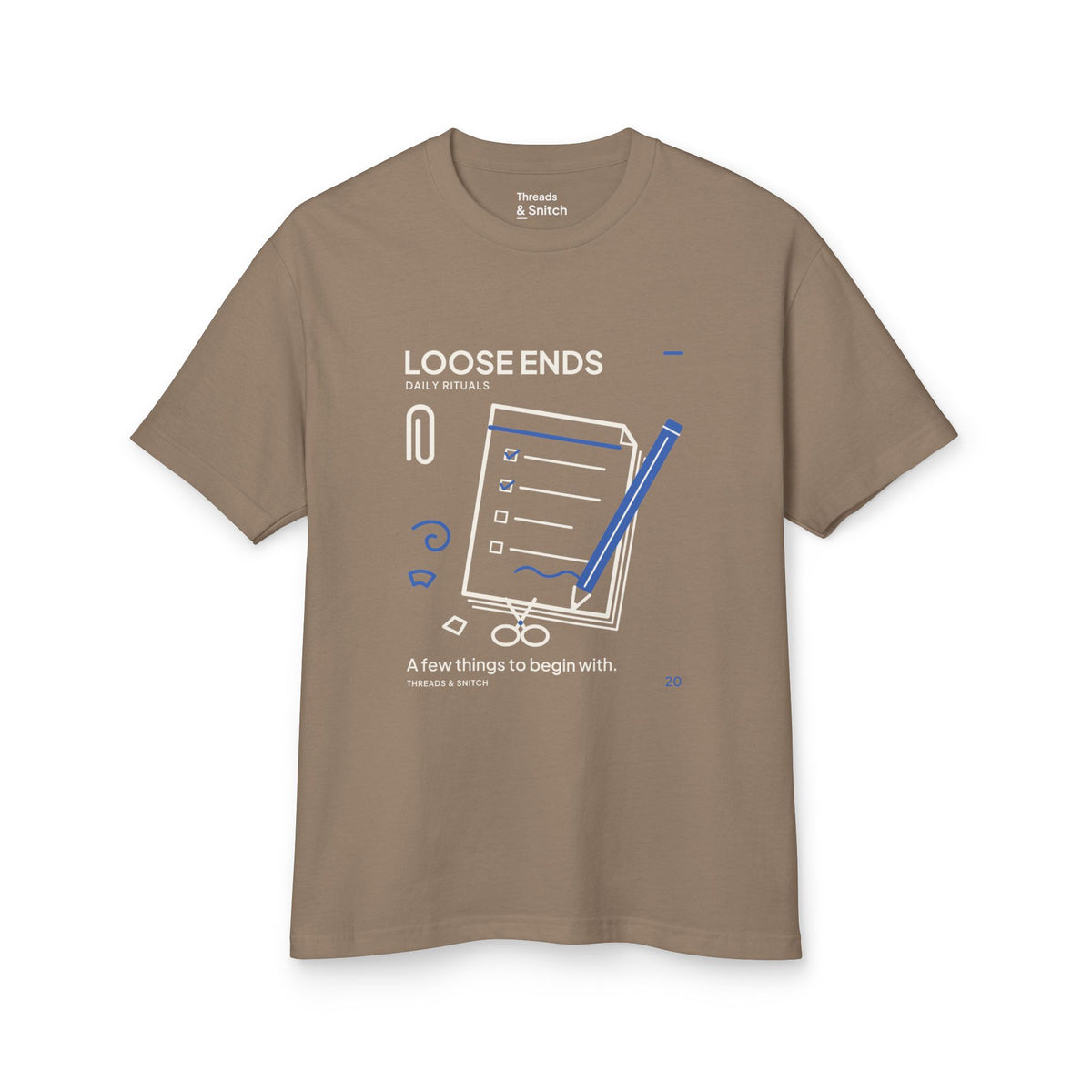 Mockup of Loose Ends Stationery Tee in Faded Brown, front view showing diagonal pencil over a task pad with scissors and a paper clip.