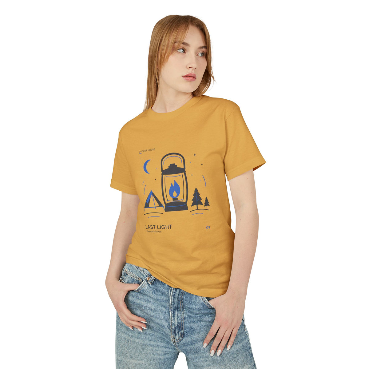 Model mockup of Last Light Lantern Graphic Tee in Faded Mustard, front view showing lantern, tent, trees and blue crescent moon.