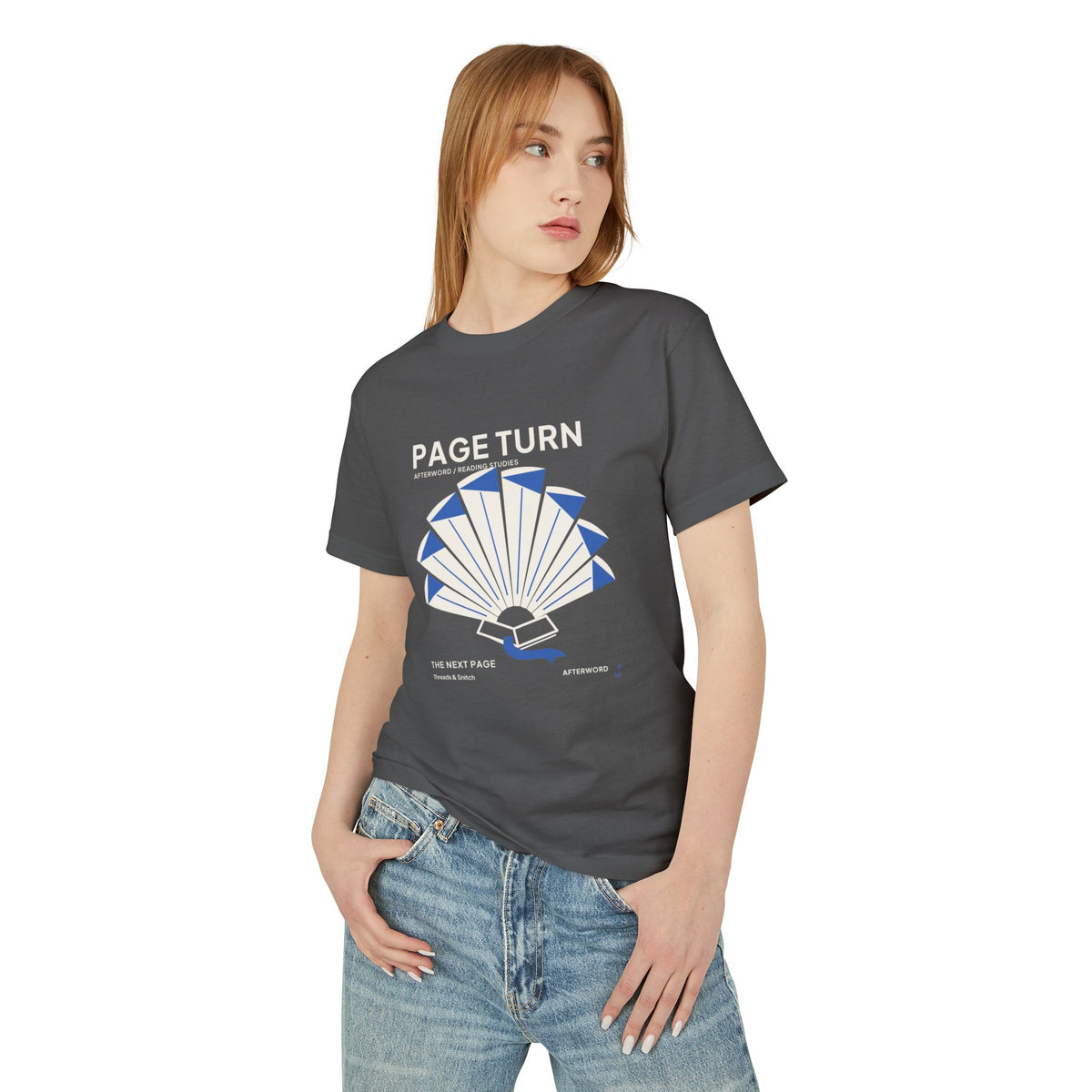 Model mockup of Page Turn Book Graphic Tee in Faded Black, front view showing book pages fanned into a radial shape with blue folds and bookmark.