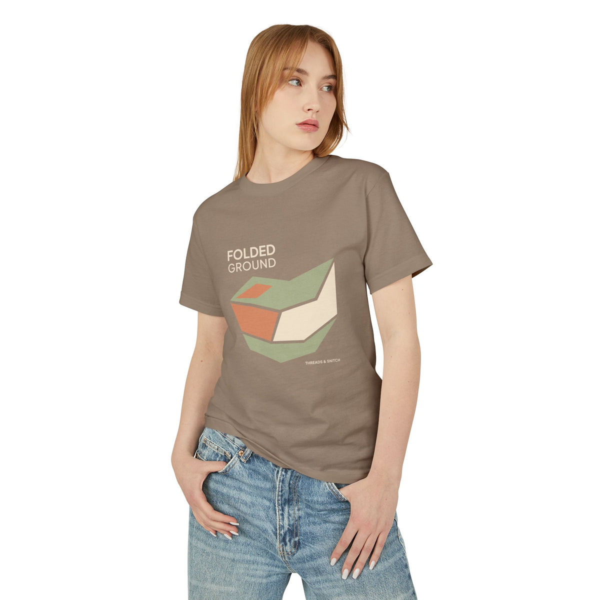 Model mockup of Folded Ground Geometric Graphic Tee in Faded Brown, front view showing angular folded planes with open channels and Folded Ground lettering.