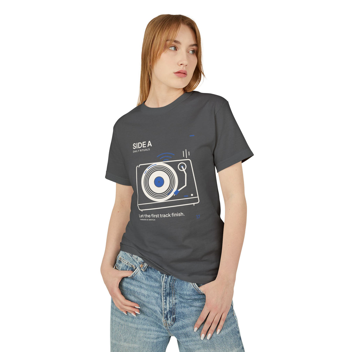 Model mockup of Side A Record Player Tee in Faded Black, front view showing record player with open circular grooves, tonearm and blue sound marks.