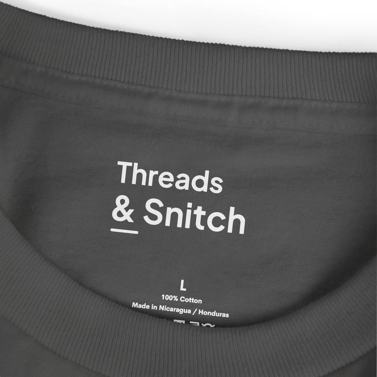 Mockup detail of the printed Threads & Snitch inner-neck label on Shade Study Geometric Graphic Tee in Faded Black.