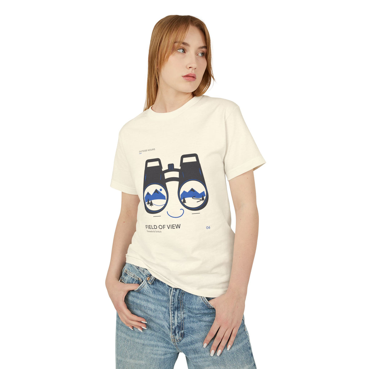Model mockup of Field of View Binoculars Tee in Faded Cream, front view showing binoculars with mountain and river landscapes inside the lenses.