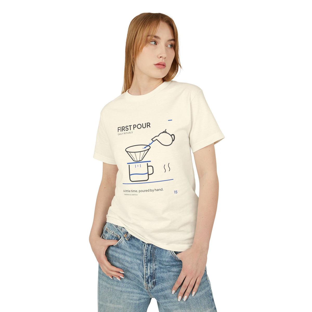 Model mockup of First Pour Coffee Graphic Tee in Faded Cream, front view showing kettle pouring blue water into a coffee filter above a brew pot.