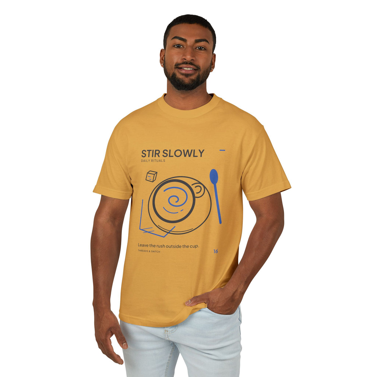 Model mockup of Stir Slowly Cup & Spoon Tee in Faded Mustard, front view showing cup and saucer with blue stirring spiral and oversized spoon.
